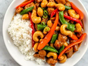 Kurczak stir-fry z orzechami nerkowca, warzywami i ryżem jaśminowym w sosie sojowym, udekorowany sezamem i szczypiorkiem